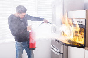 Man putting out oven fire with fire extinguisher