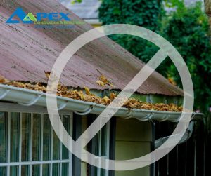 Leaf-clogged gutter that is partially detached from a roof.