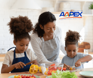A woman and two children preparing meal in a trendy kitchen. Aapex logo top right.