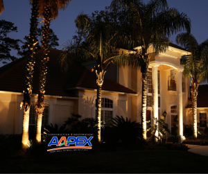 A home at night with uplighting on trees. Aapex logo bottom left.