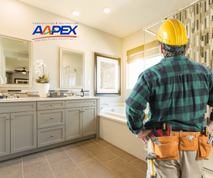 Professional contractor examining a bathroom with his hands on his hips. Aapex logo top left.