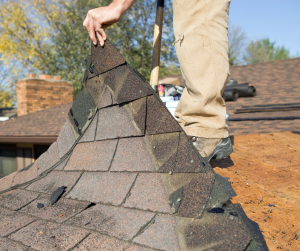 A roofer tearing off old shingles.