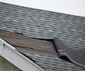 Shingles on a roof that have been peeled off.